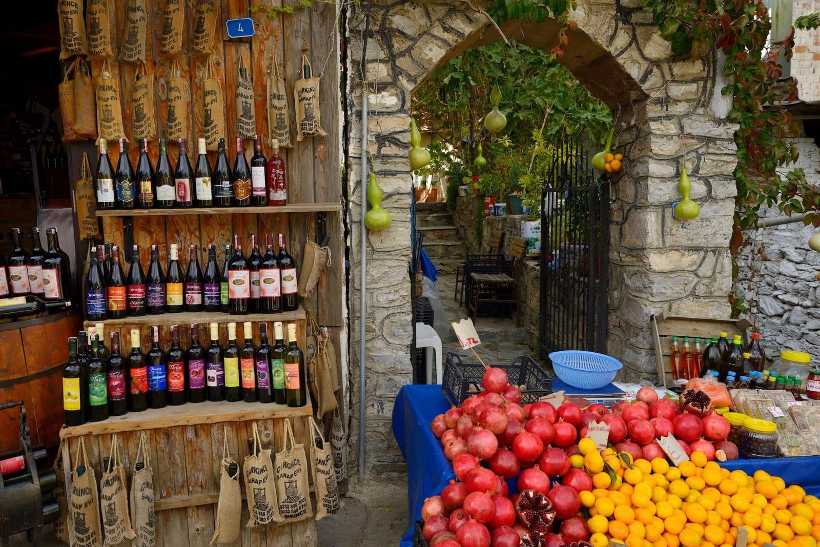 Shelves of wine bottles beside crates of fruit at a stone shop. Avanos Wine Tasting, arranged from The Owl Cave Hotel in Göreme, Cappadocia.