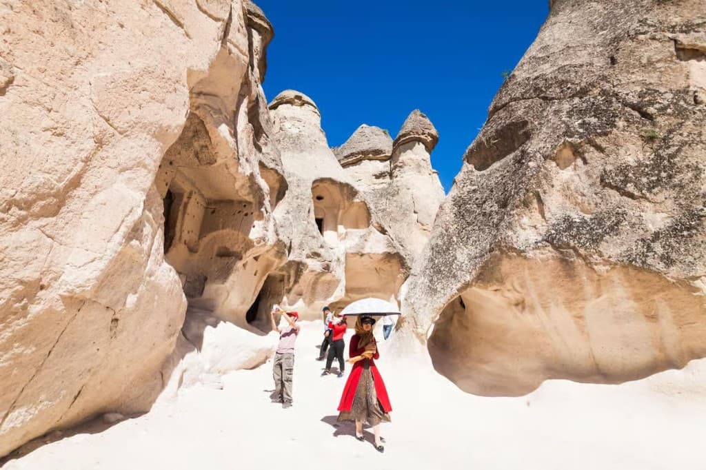 Guests walking among cave dwellings and white tuff cones on the Cappadocia Red Tour from The Owl Cave Hotel