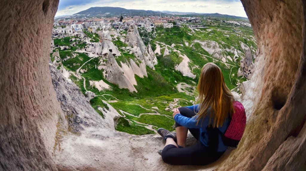 Guest sitting in a cave window overlooking a Cappadocia village on the Red Tour from The Owl Cave Hotel, Göreme
