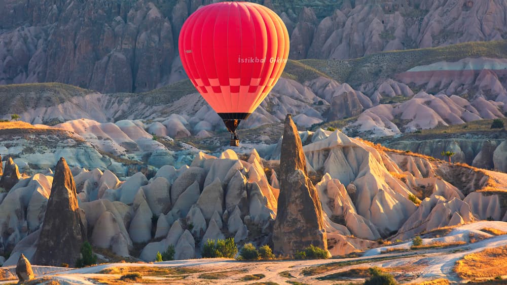 Hot air balloon drifting over Cappadocia fairy chimneys on the Göreme Sunrise Balloon Flight from The Owl Cave Hotel
