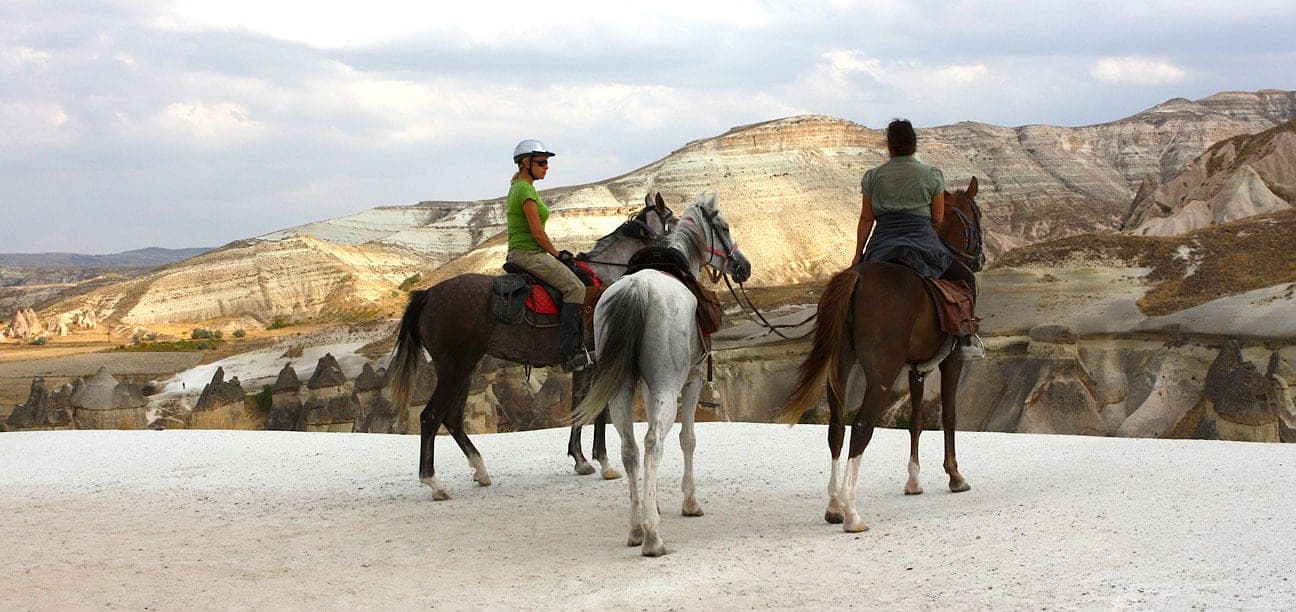 Two riders on a pale road among fairy chimneys. Fairy Chimney Horse Ride, arranged from The Owl Cave Hotel in Göreme, Cappadocia.