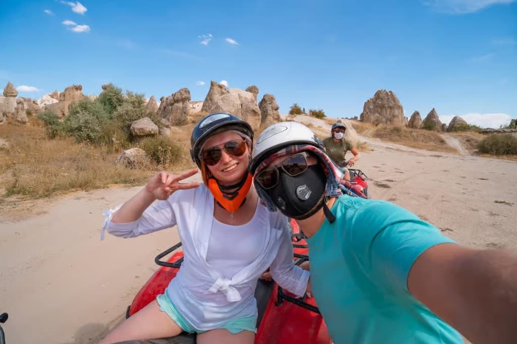 Guests wearing helmets on a red ATV among fairy chimneys on the Göreme Quad Safari from The Owl Cave Hotel, Cappadocia