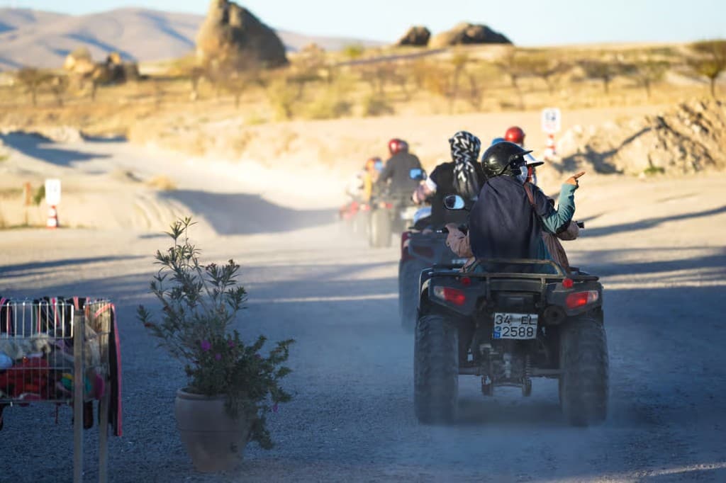 Guided quad convoy on a dusty Göreme road during the Quad Safari arranged from The Owl Cave Hotel, Cappadocia