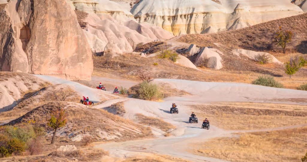 ATVs riding Rose Valley tracks among pastel tuff hills on the Göreme Quad Safari from The Owl Cave Hotel, Cappadocia