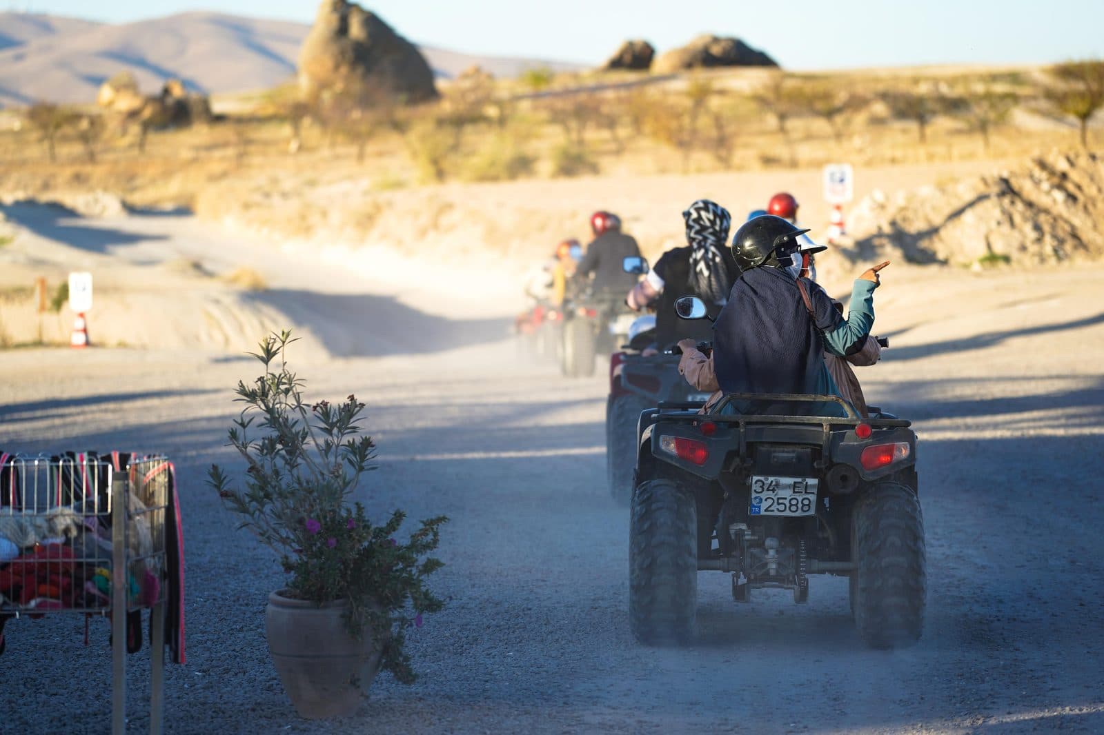 Riders on ATVs heading down a road past fairy chimneys. Sunset ATV Safari, arranged from The Owl Cave Hotel in Göreme, Cappadocia.