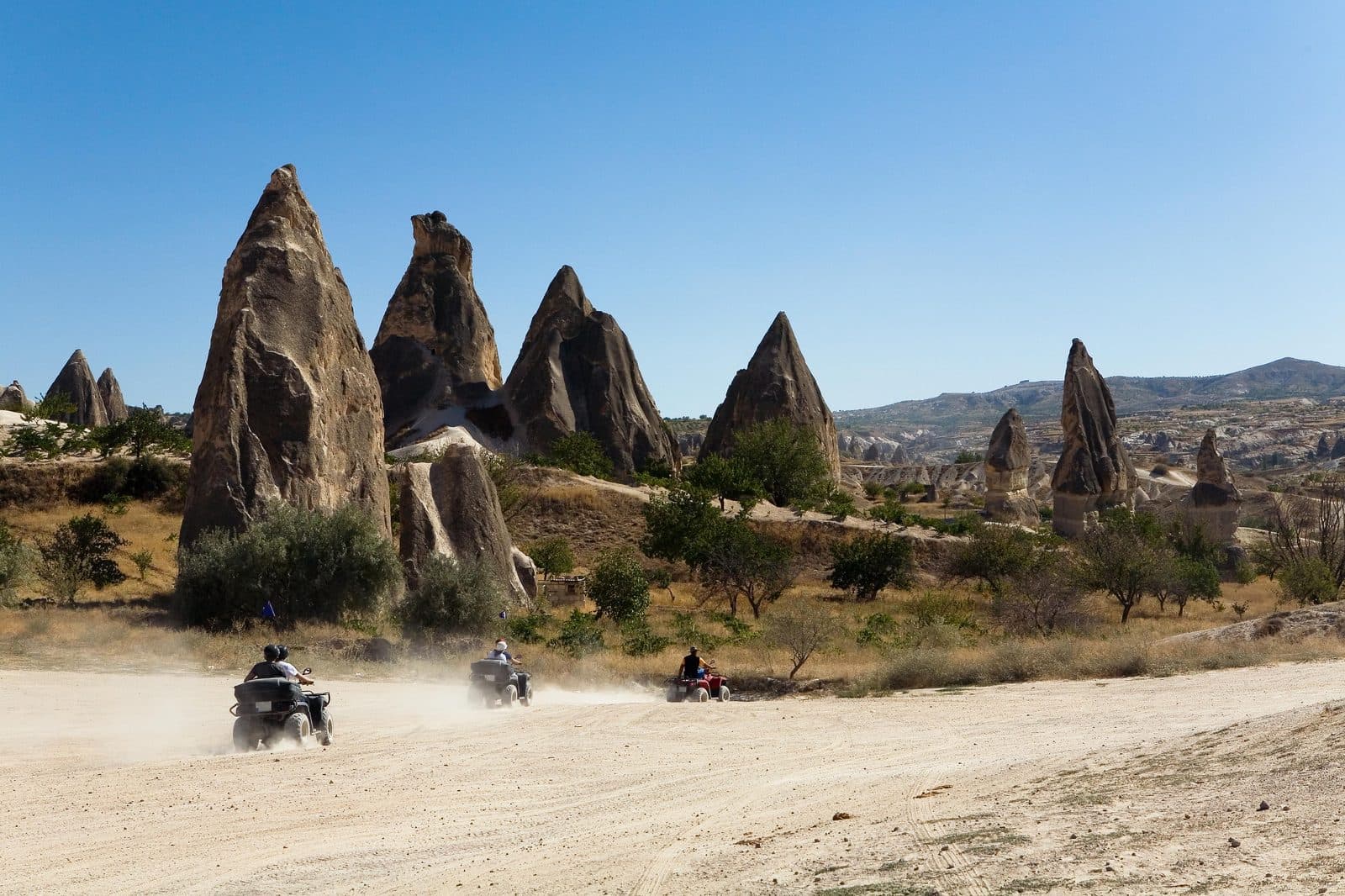 ATVs kicking up dust past tall fairy chimneys. Sunset ATV Safari, arranged from The Owl Cave Hotel in Göreme, Cappadocia.