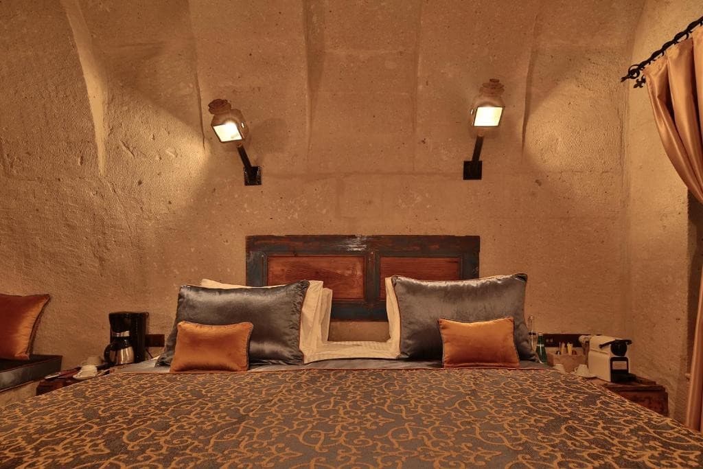Deluxe Arch Room with View king bed with painted wooden headboard at The Owl Cave Hotel in Göreme