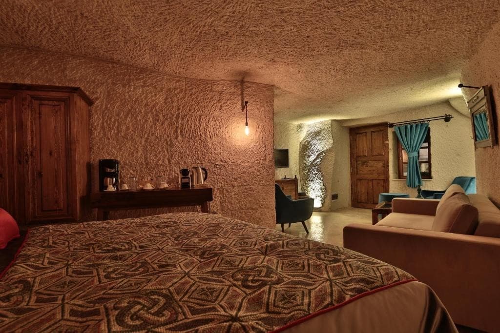 Bookable Deluxe King Suite in Göreme showing the king bedroom, seating area, and terrace door at The Owl Cave Hotel, Cappadocia