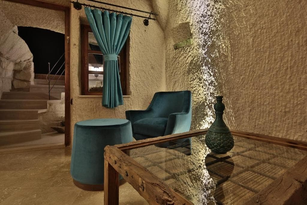 Deluxe King Suite seating area with terrace stairs and balcony window at The Owl Cave Hotel, Göreme, Cappadocia