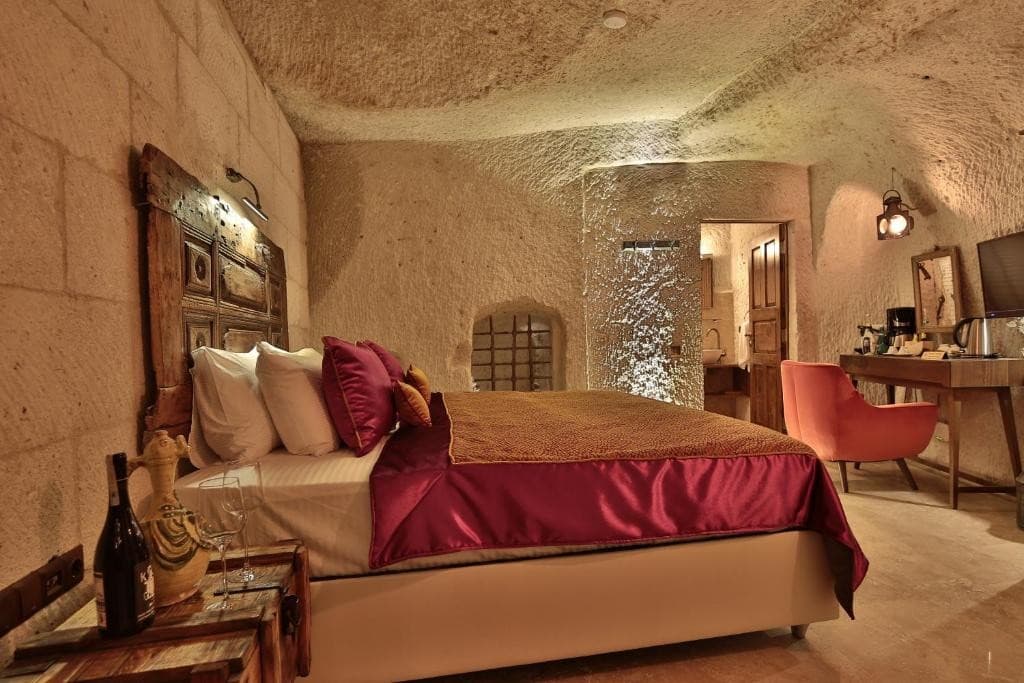 Bookable Premier Cave Room in Göreme showing the king bed, seating, and private bathroom at The Owl Cave Hotel