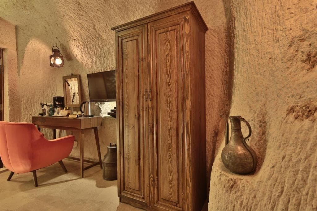 Wooden wardrobe and seating area in the bookable Premier Cave Room at The Owl Cave Hotel, Göreme