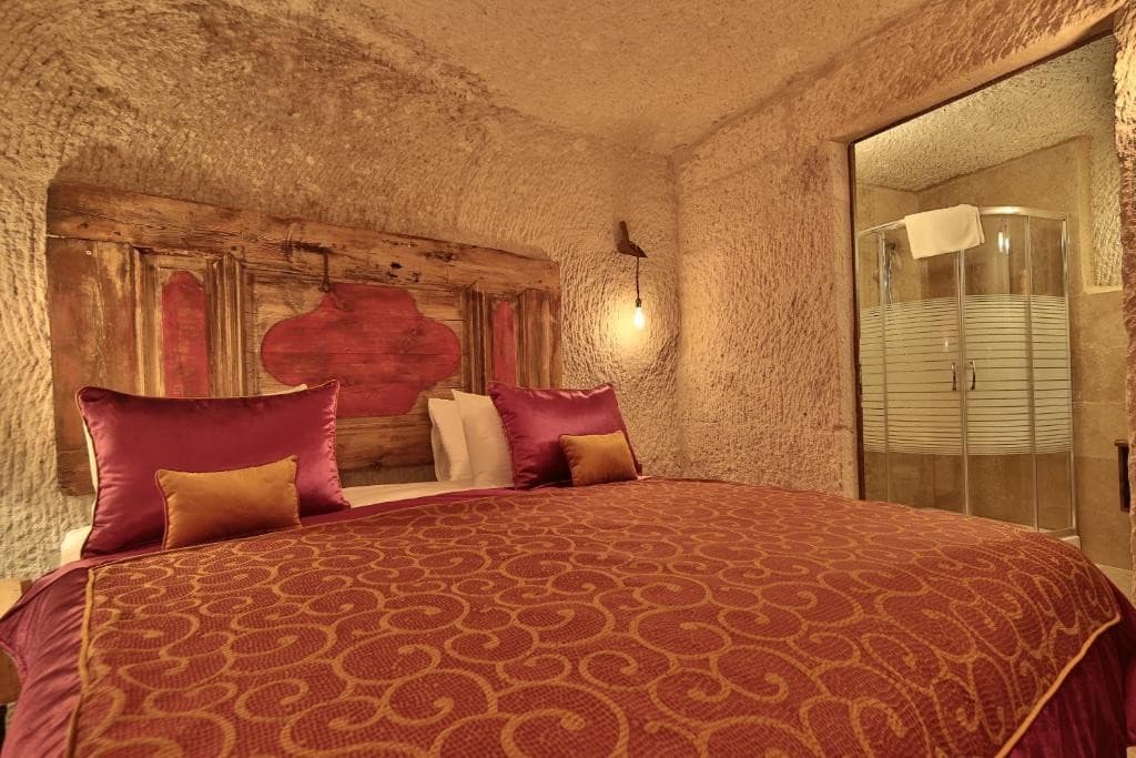 Bookable Superior Cave Room in Göreme showing the king bed and private bathroom shower at The Owl Cave Hotel