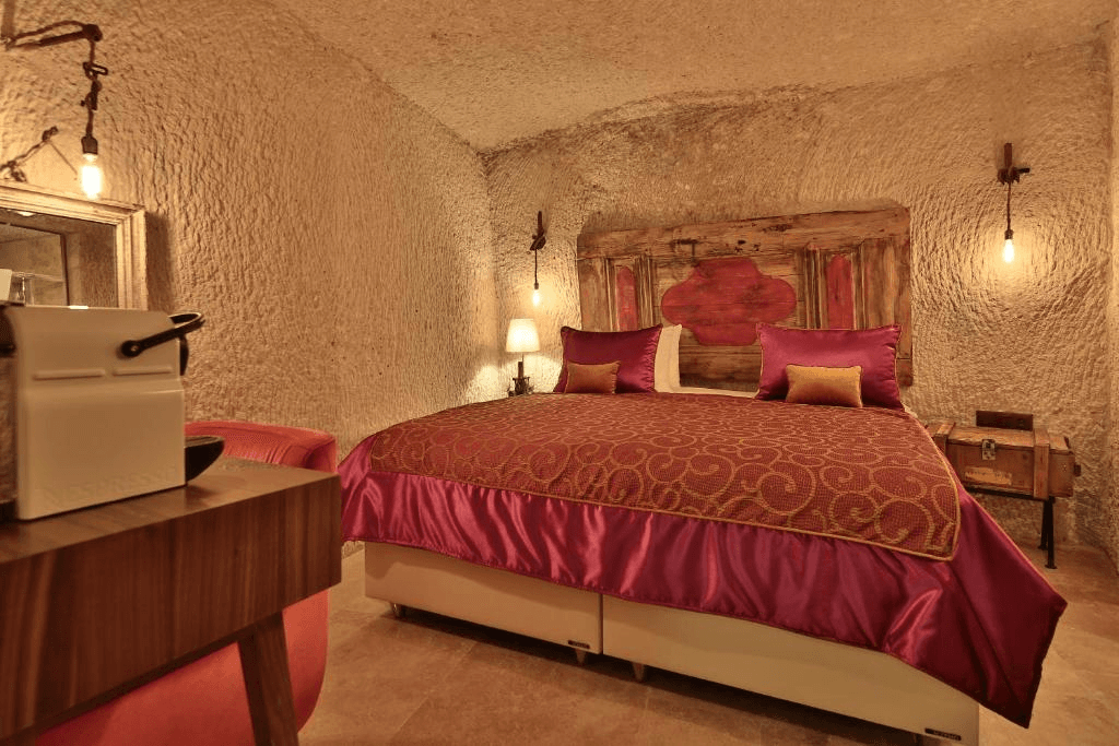 Superior Cave Room cave interior with coffee machine, seating, and king bed at The Owl Cave Hotel in Göreme