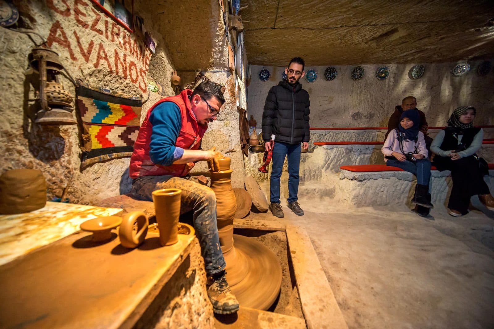 A cave workshop in Avanos, with a potter at the wheel and guests seated. Avanos Pottery Workshop, arranged from The Owl Cave Hotel in Göreme, Cappadocia.