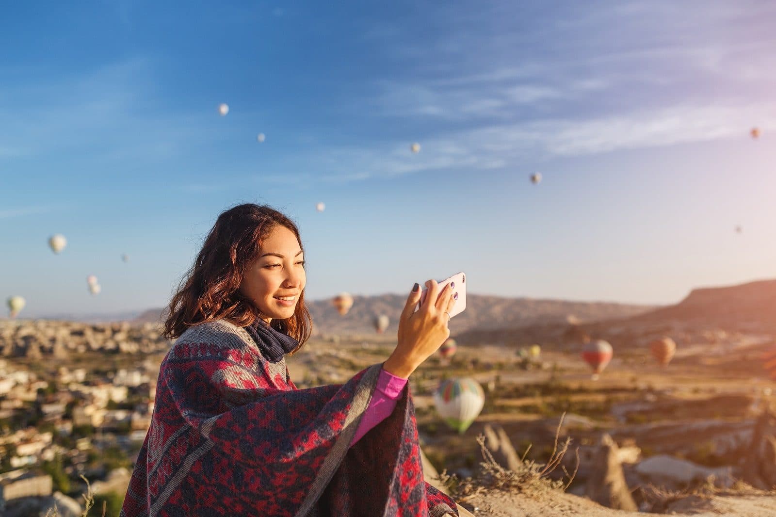 A guest photographing hot air balloons at sunrise over a Cappadocia town. Sunrise Balloon and Cappadocia Day, arranged from The Owl Cave Hotel in Göreme, Cappadocia.