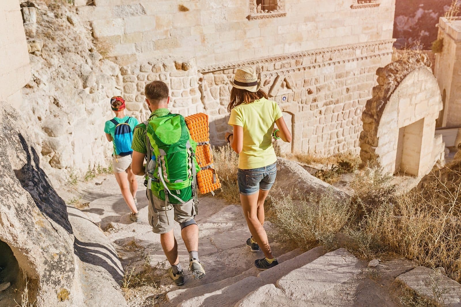 Three guests walking toward a cave entrance. Sunrise Balloon and Cappadocia Day, arranged from The Owl Cave Hotel in Göreme, Cappadocia.