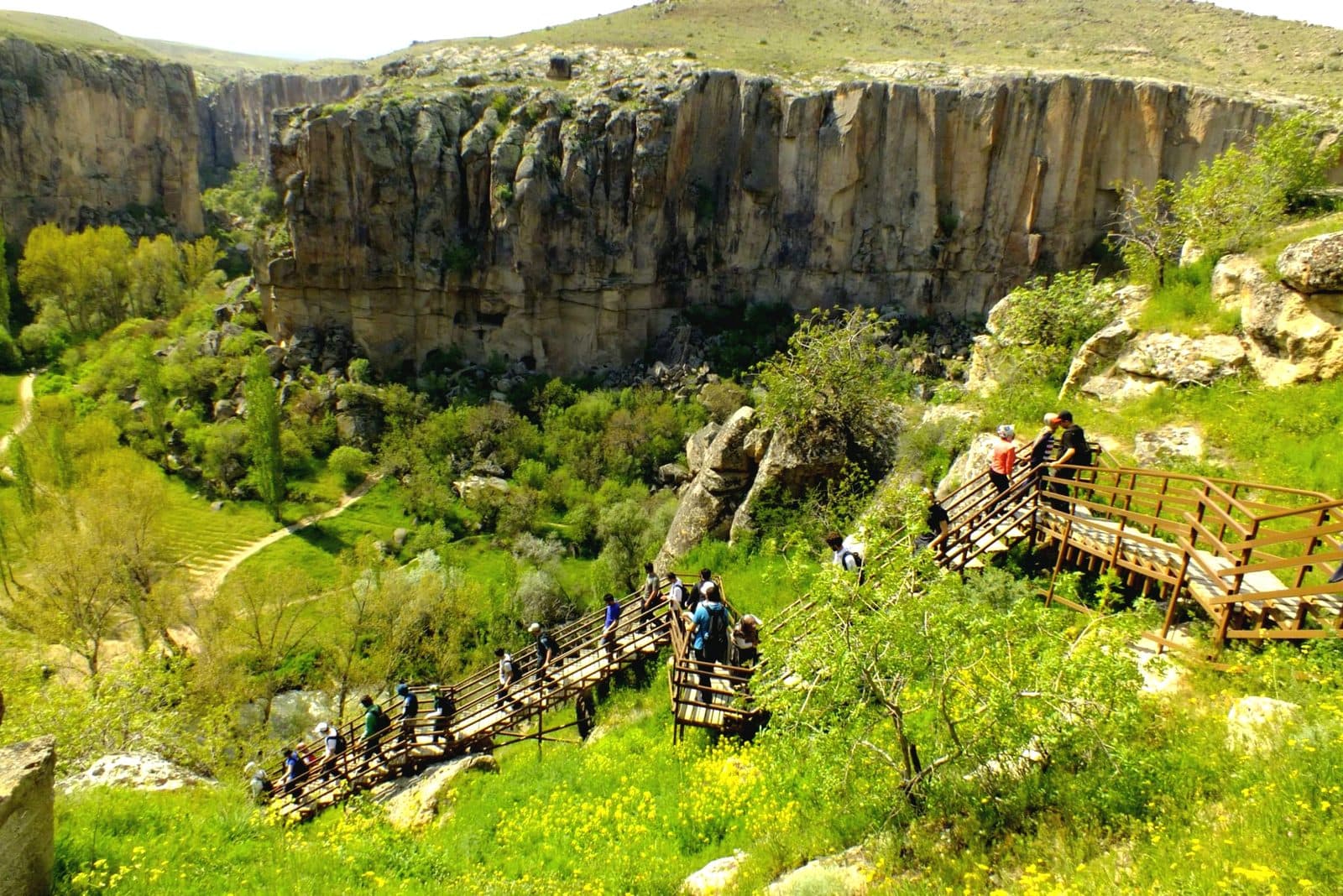 Hikers on a wooden walkway in a green canyon. Green Tour with Narlıgöl, arranged from The Owl Cave Hotel in Göreme, Cappadocia.