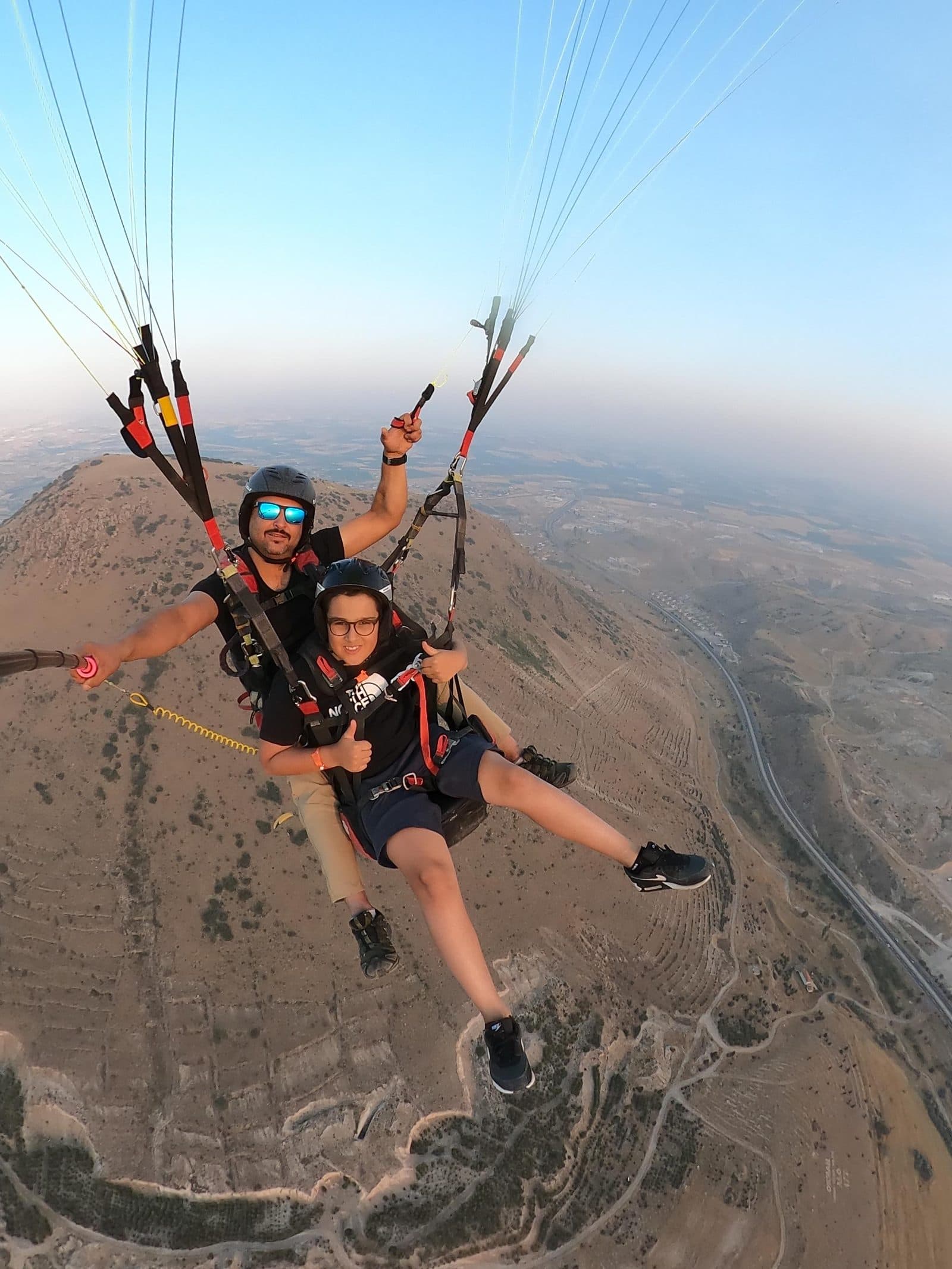 A tandem pair over hazy hills. Tandem Paragliding, arranged from The Owl Cave Hotel in Göreme, Cappadocia.