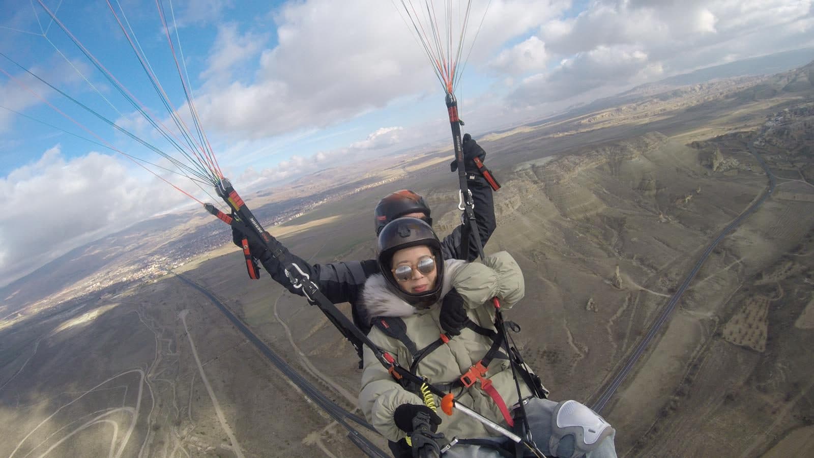 A tandem pair flying over a canyon. Tandem Paragliding, arranged from The Owl Cave Hotel in Göreme, Cappadocia.