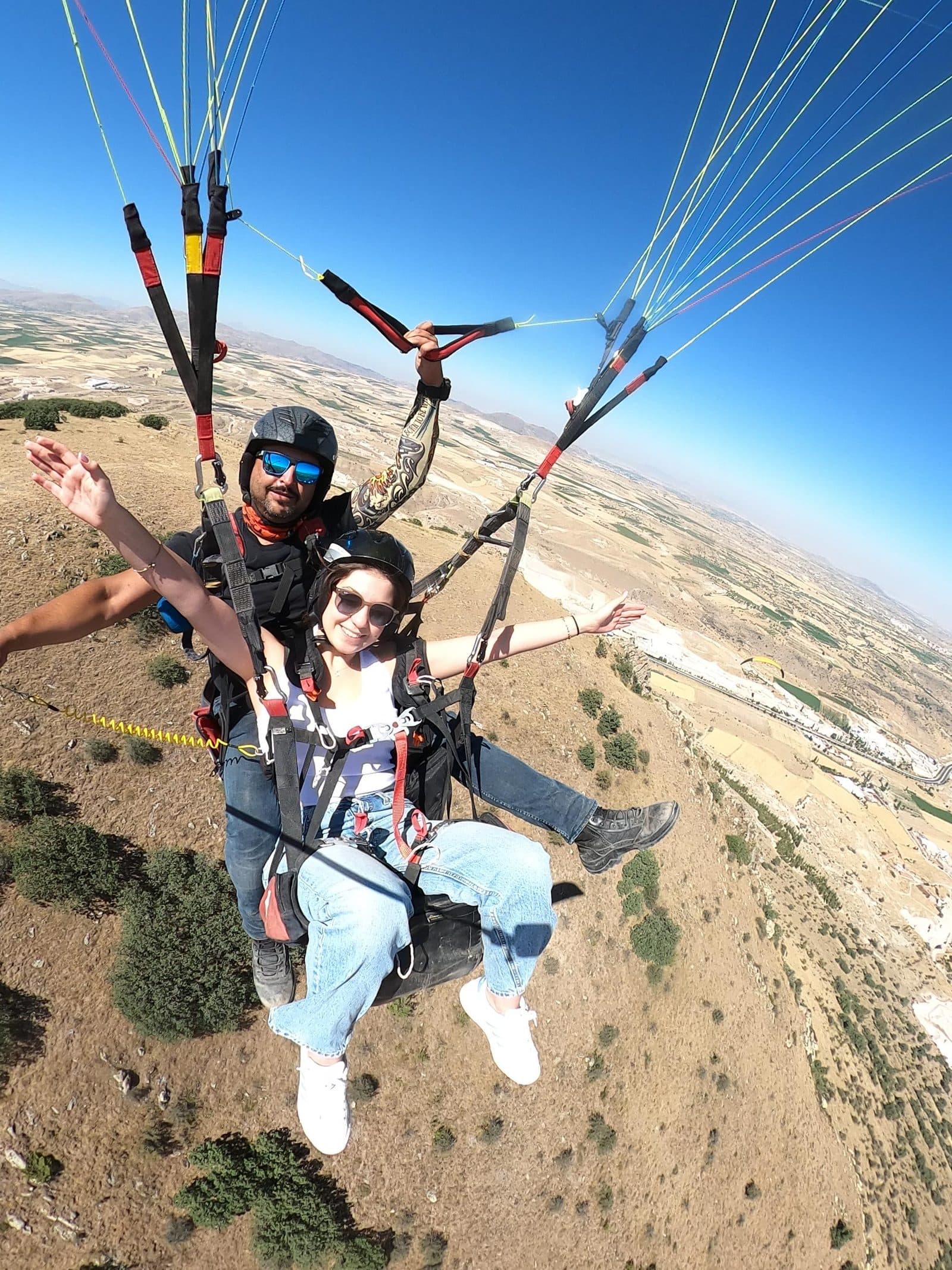 A tandem selfie, the passenger’s arms out over the valley. Tandem Paragliding, arranged from The Owl Cave Hotel in Göreme, Cappadocia.