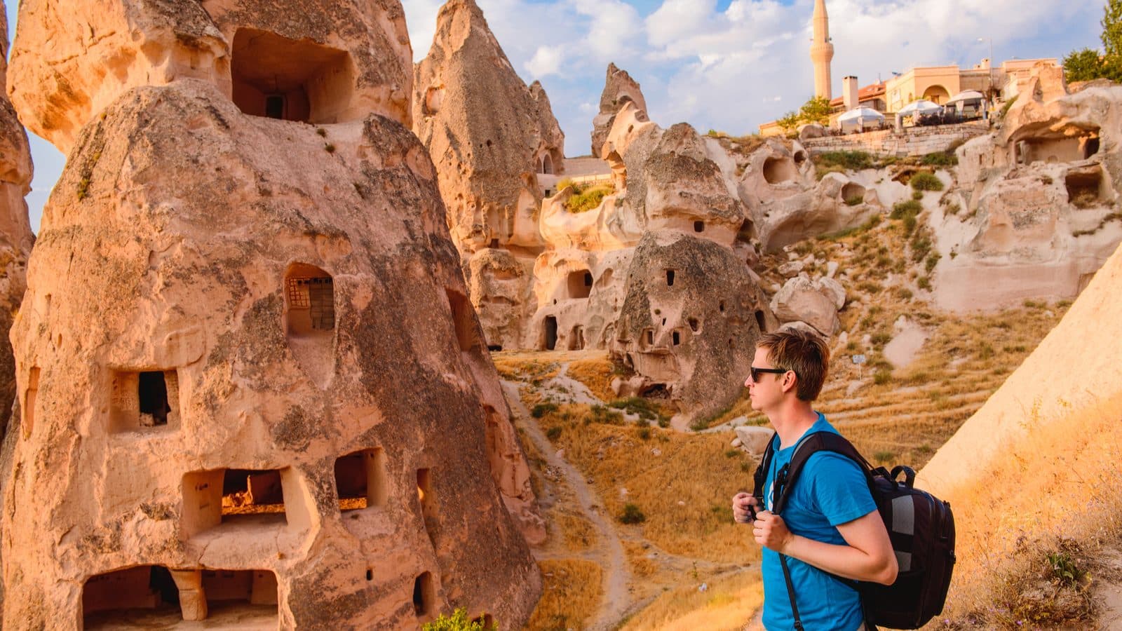 A guest looking at a cave facade pierced with small windows. Cappadocia Red and Green Day, arranged from The Owl Cave Hotel in Göreme, Cappadocia.
