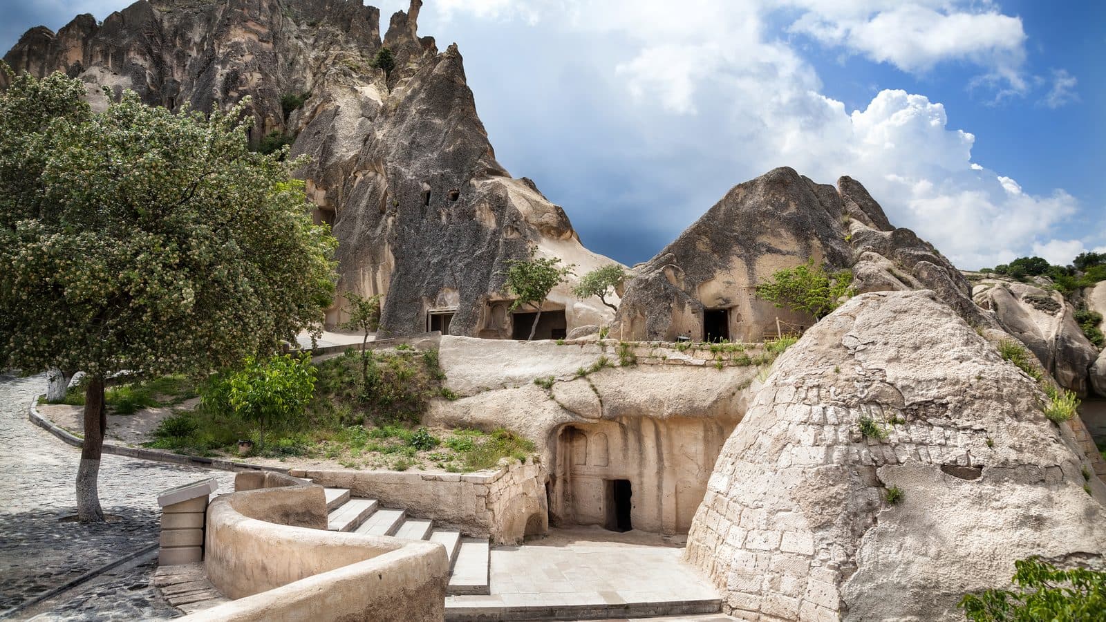 A small rock-cut house and path among fairy chimneys. Cappadocia Red and Green Day, arranged from The Owl Cave Hotel in Göreme, Cappadocia.