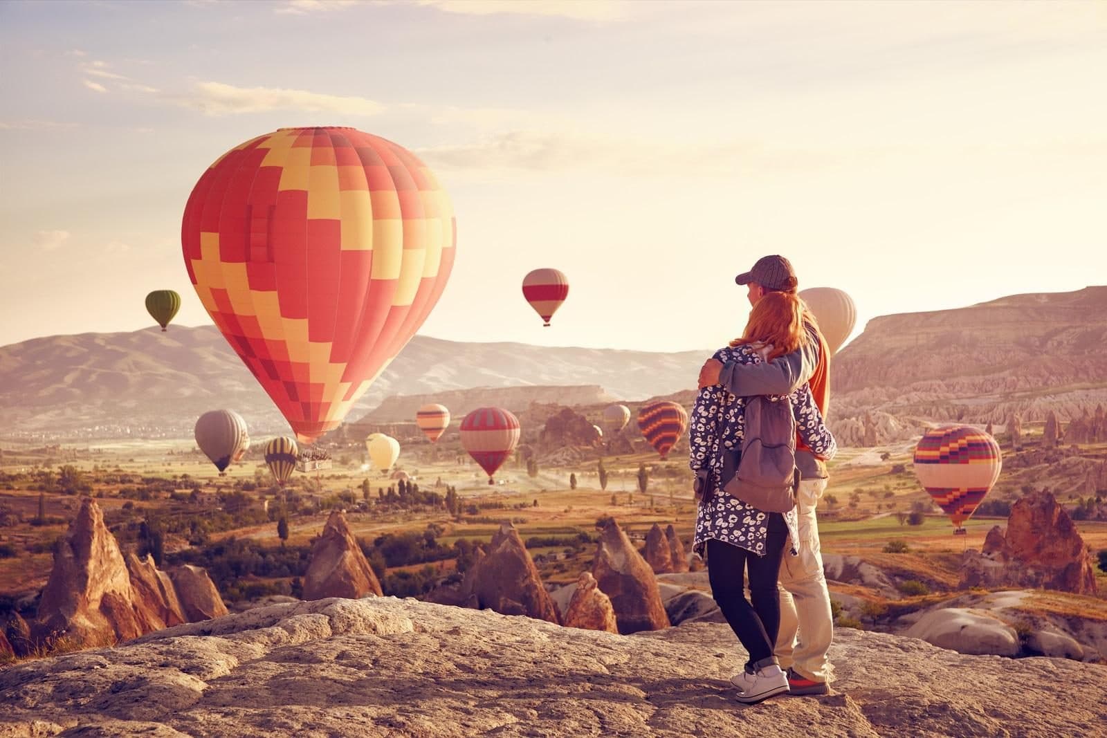 A guest standing beside a red and yellow balloon. Sunrise Balloon Watching, arranged from The Owl Cave Hotel in Göreme, Cappadocia.