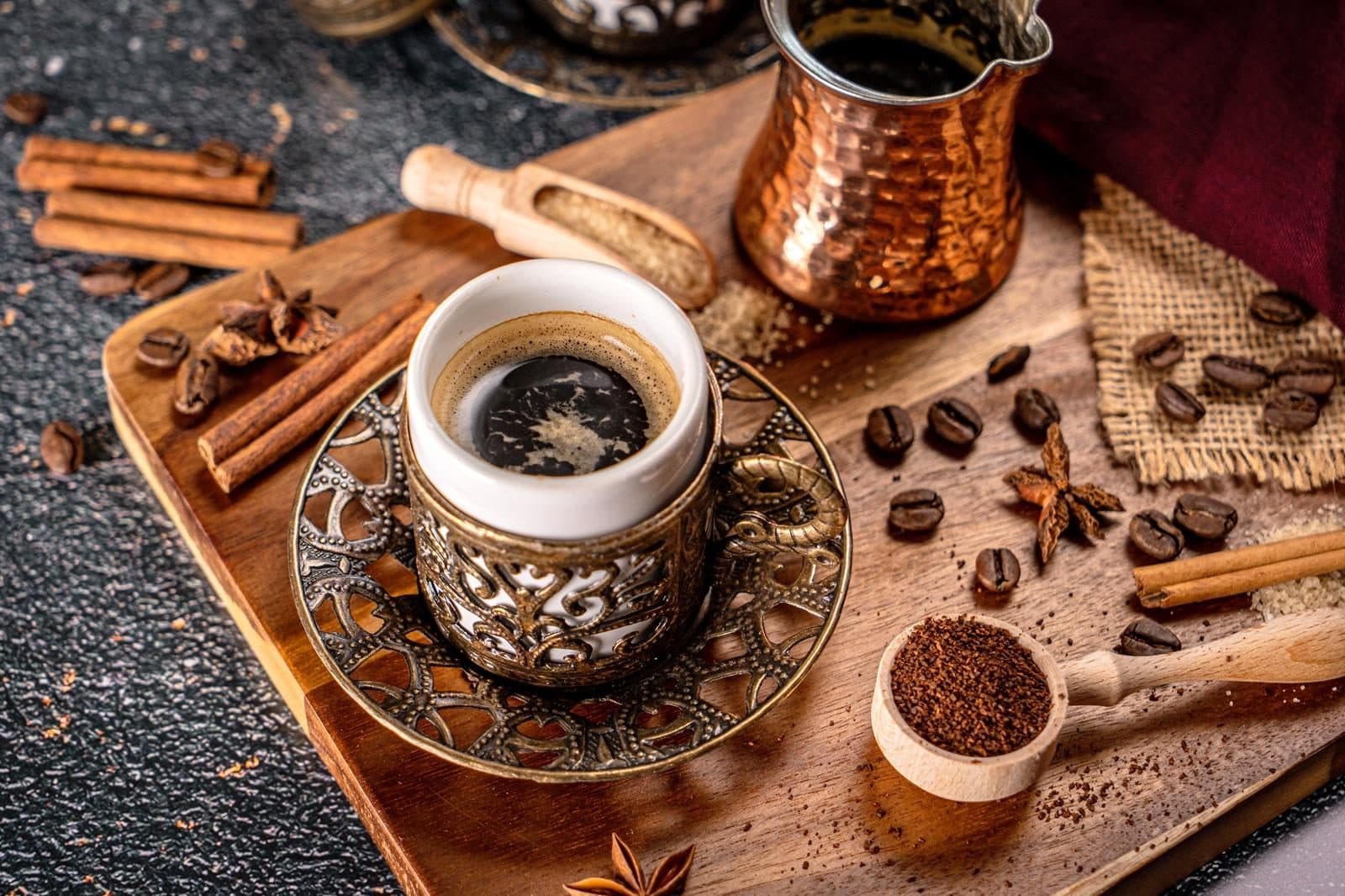 A cup of Turkish coffee on a metal tray with cinnamon and coffee beans. Sand-Brewed Turkish Coffee Workshop, arranged from The Owl Cave Hotel in Göreme, Cappadocia.