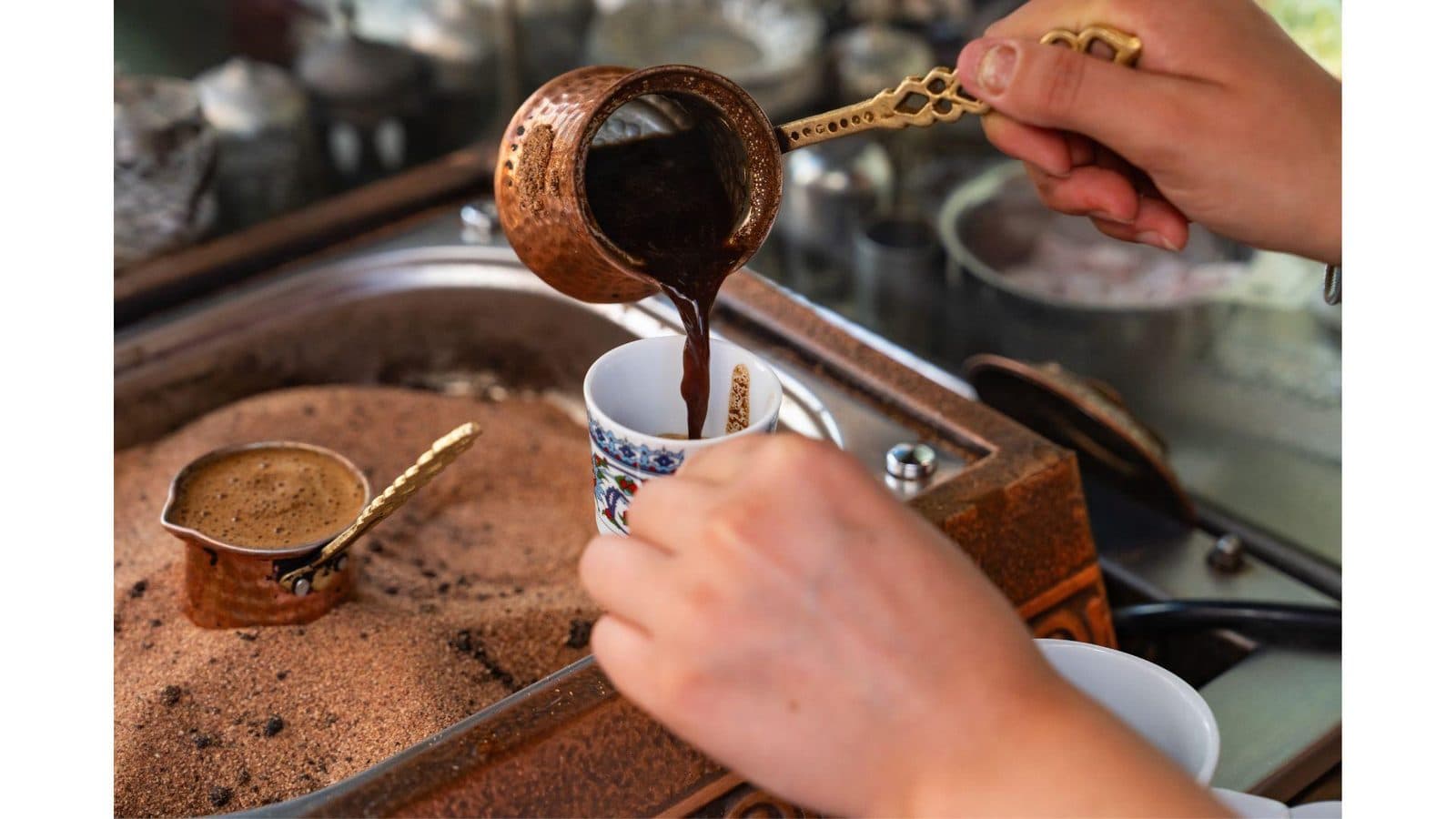 Turkish coffee poured from a copper cezve into a cup, with a sand tray beside it. Sand-Brewed Turkish Coffee Workshop, arranged from The Owl Cave Hotel in Göreme, Cappadocia.