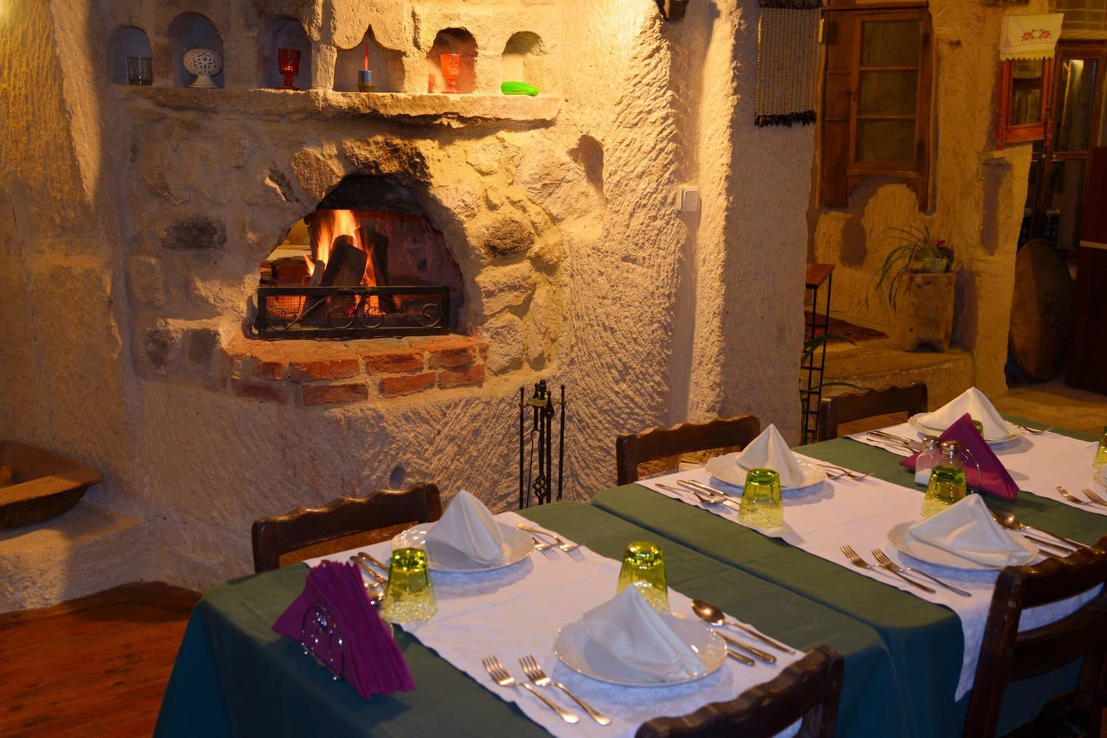 A set table beside a stone fireplace. Turkish Night at a Cave Restaurant, arranged from The Owl Cave Hotel in Göreme, Cappadocia.